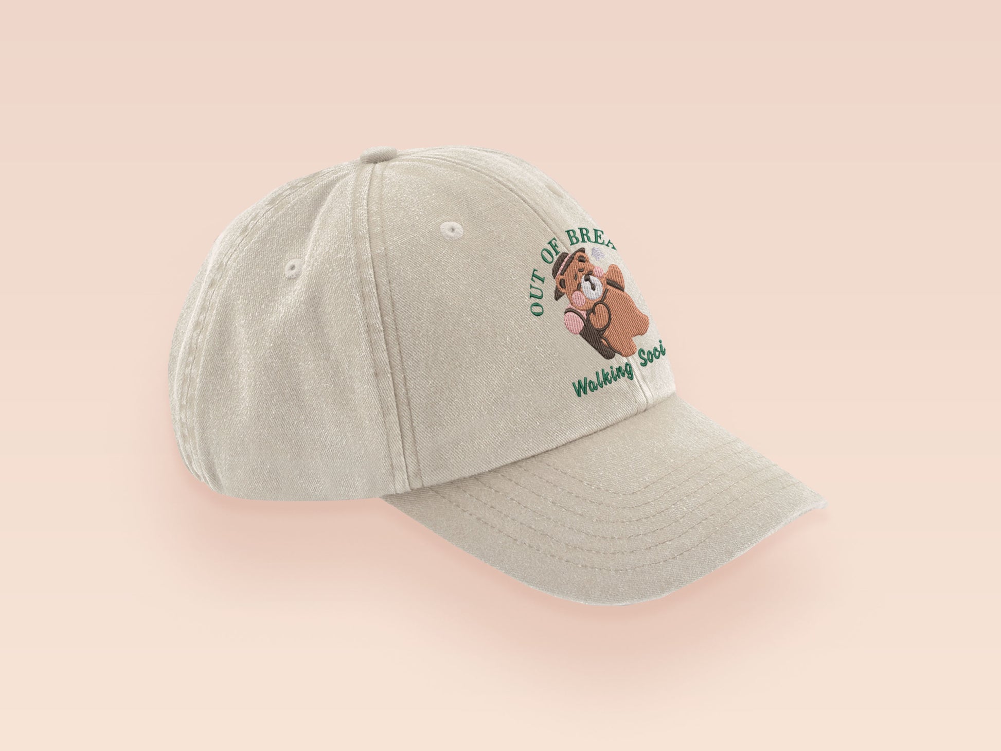 A cream baseball cap hat with an embroidered cute brown bear hiking with the quote out of breath walking society.