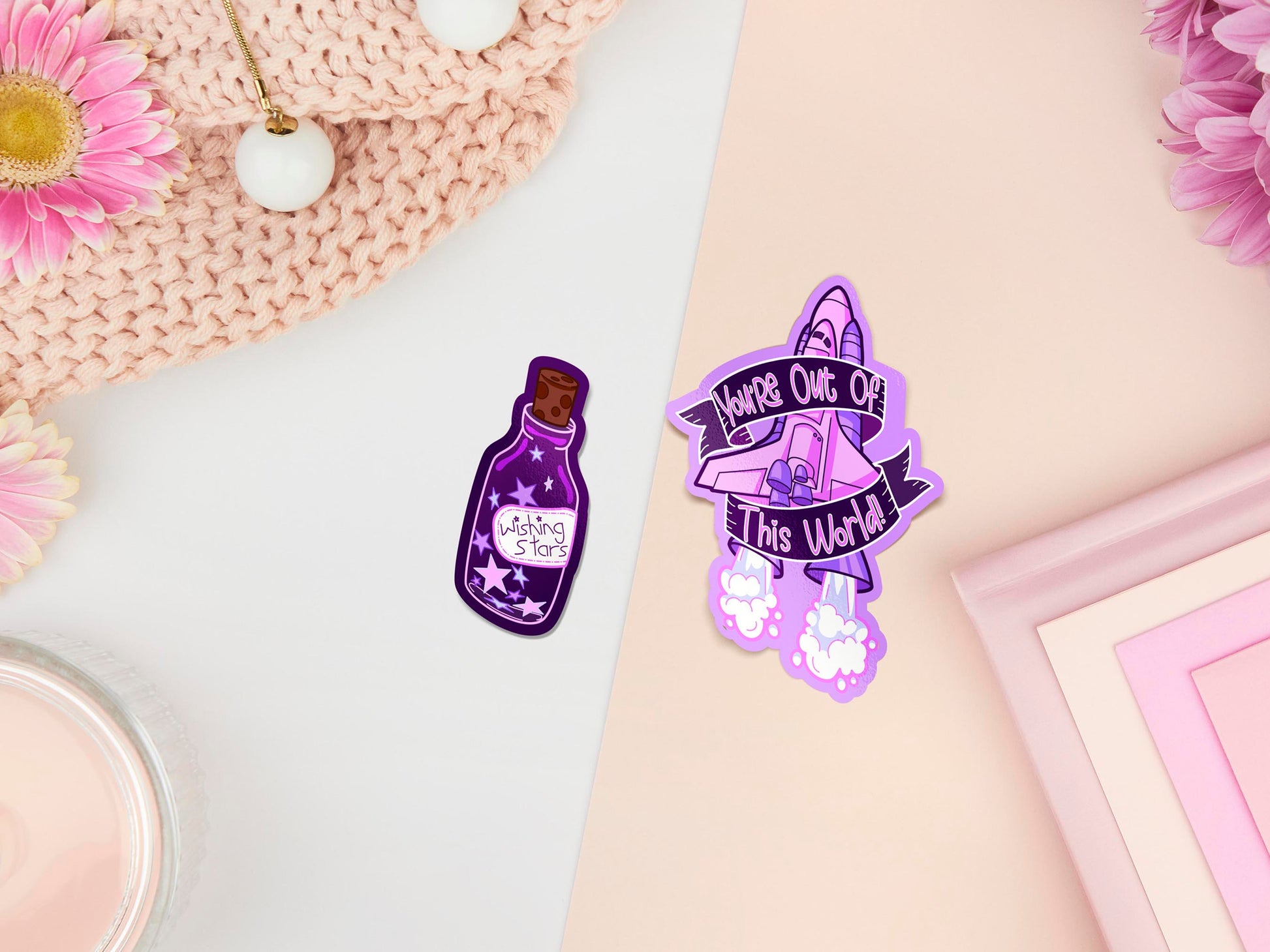 Two stickers of digitally illustrated cartoons, one is a bottle filled with star labelled wishing stars, the other is a space rocket blasting of with the words you're out of this world