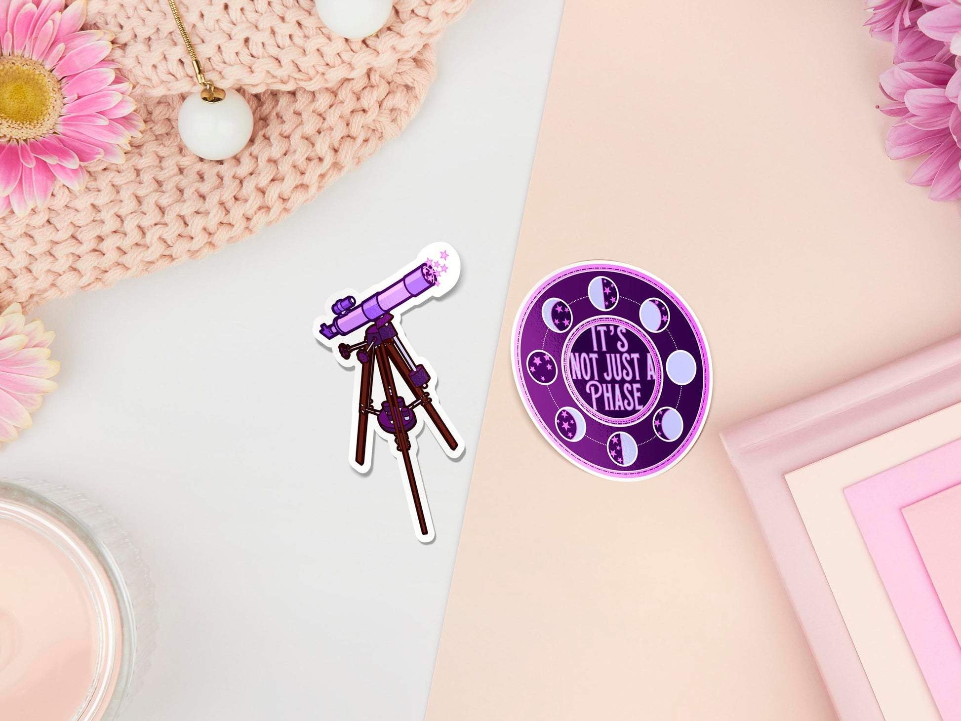Two stickers of digitally illustrated cartoons one is a telescope, the other is the quote it's not just a phase, surrounded by the different phases of the moon
