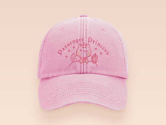 A vintage pink baseball cap hat with an embroidered cute princess cat wearing a seatbelt and holding a boba bubble tea drink with the quote Passenger Princess