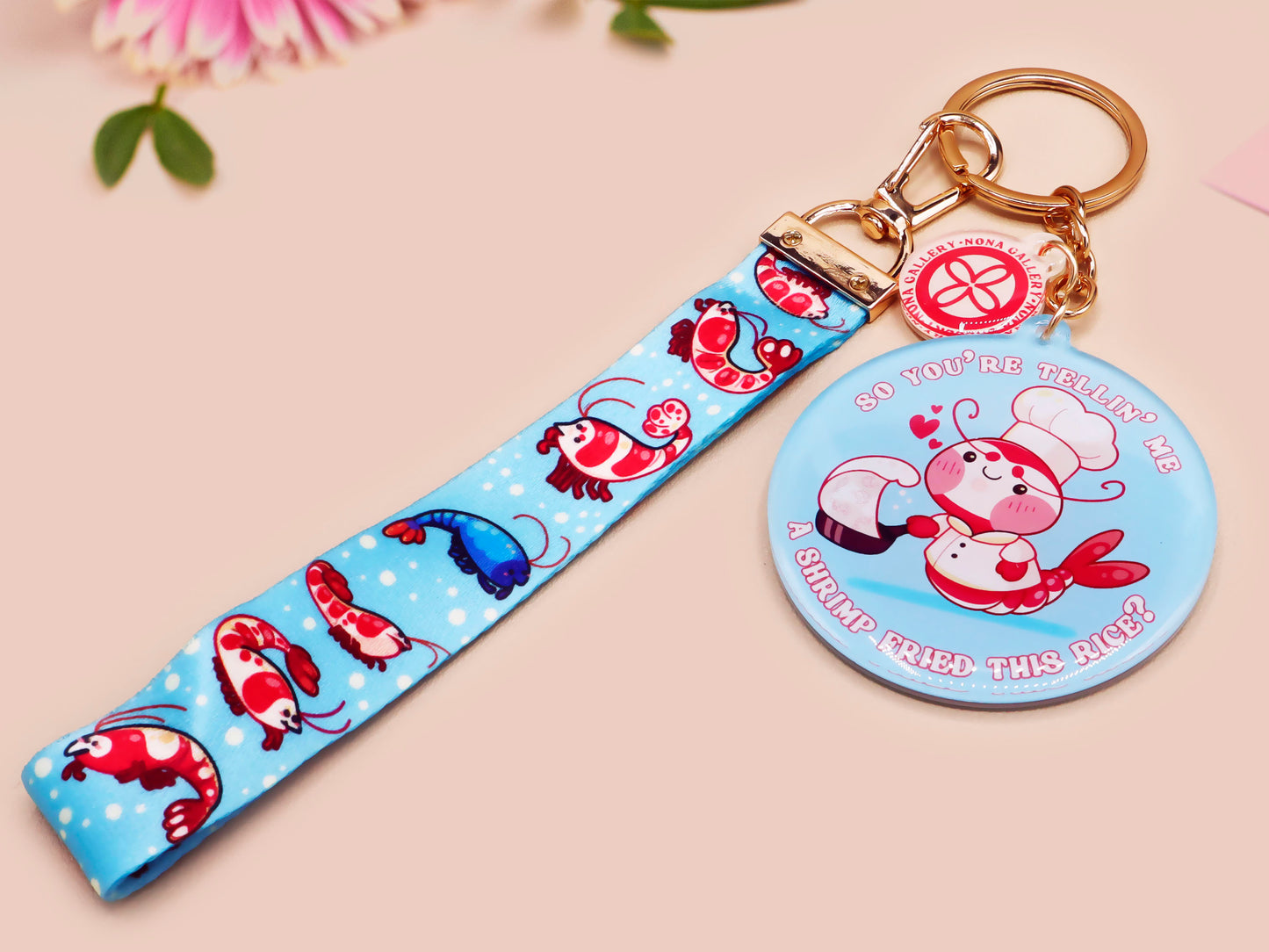 Acrylic epoxy shrimp keychain with a large acrylic charm of a a chef shrimp frying rice in a pan with the quote so you're telling me a shrimp fried this rice, a smaller charm of a cute baby shrimp and a matching blue shrimp lanyard.