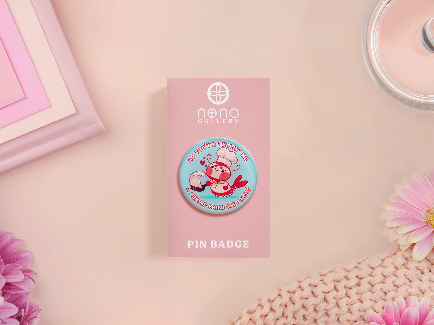 A clear acrylic pin badge with a pink heart-shaped pin back clasp. The design of the pin badge is of a cute chibi shrimp in a chefs outfit cooking with the quote So you're telling me a shrimp fried this rice?