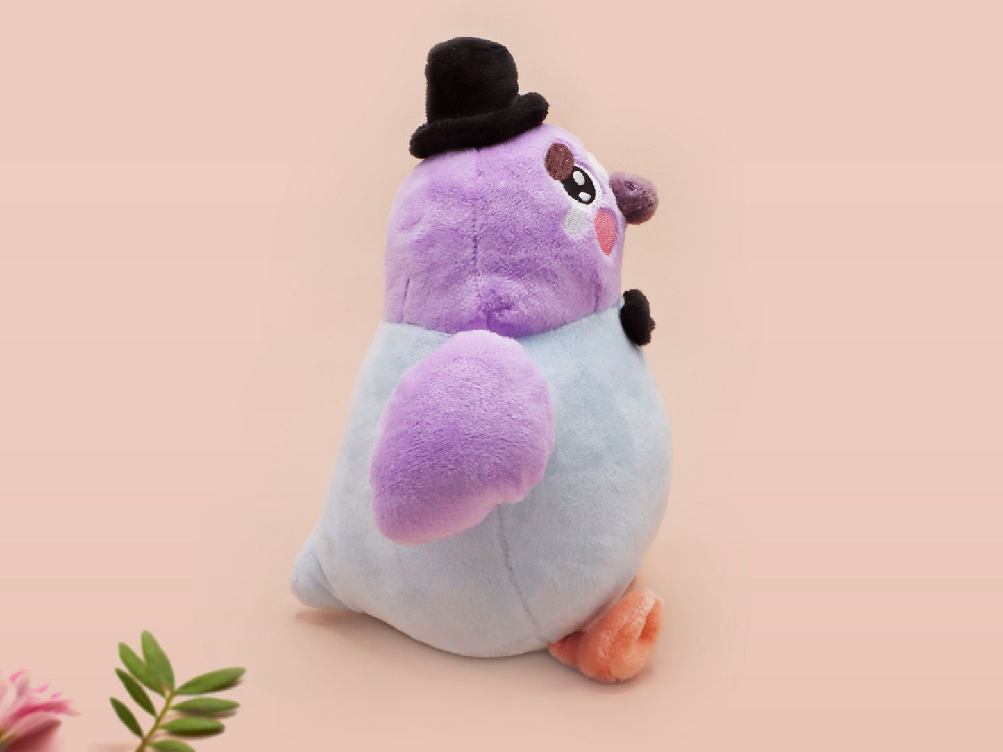An adorable purple and blue pigeon bird plushie toy with cute embroidered eyes and facial expression, wearing a black top hat and bow tie, with a hang tag describing the pigeon as Susan.