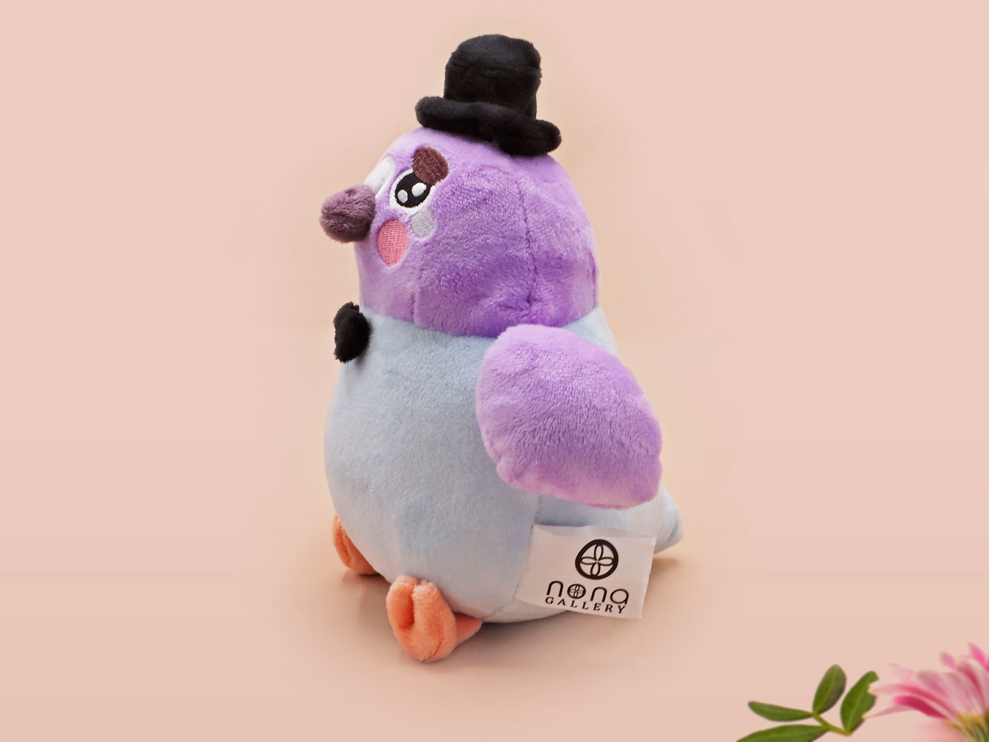 An adorable purple and blue pigeon bird plushie toy with cute embroidered eyes and facial expression, wearing a black top hat and bow tie, with a hang tag describing the pigeon as Susan.