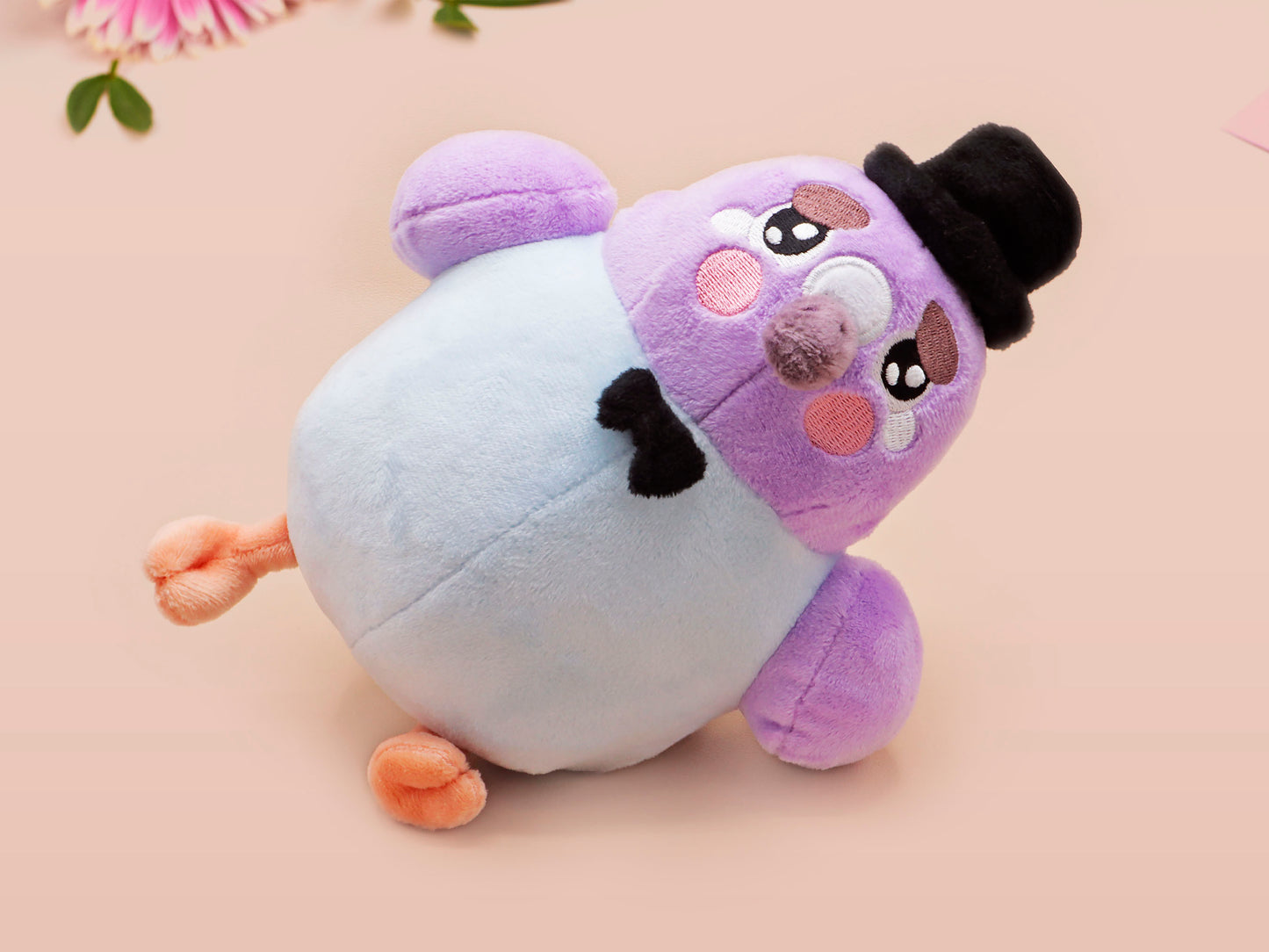 An adorable purple and blue pigeon bird plushie toy with cute embroidered eyes and facial expression, wearing a black top hat and bow tie, with a hang tag describing the pigeon as Susan.