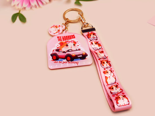 Cute pink keychain and lanyard of an adorable chibi hamster guinea pig in heart sunglasses driving a little pink car with the quote the Horrors do be persisting, with matching mini charm and lanyard of multiple cute fat guinea pig hamsters