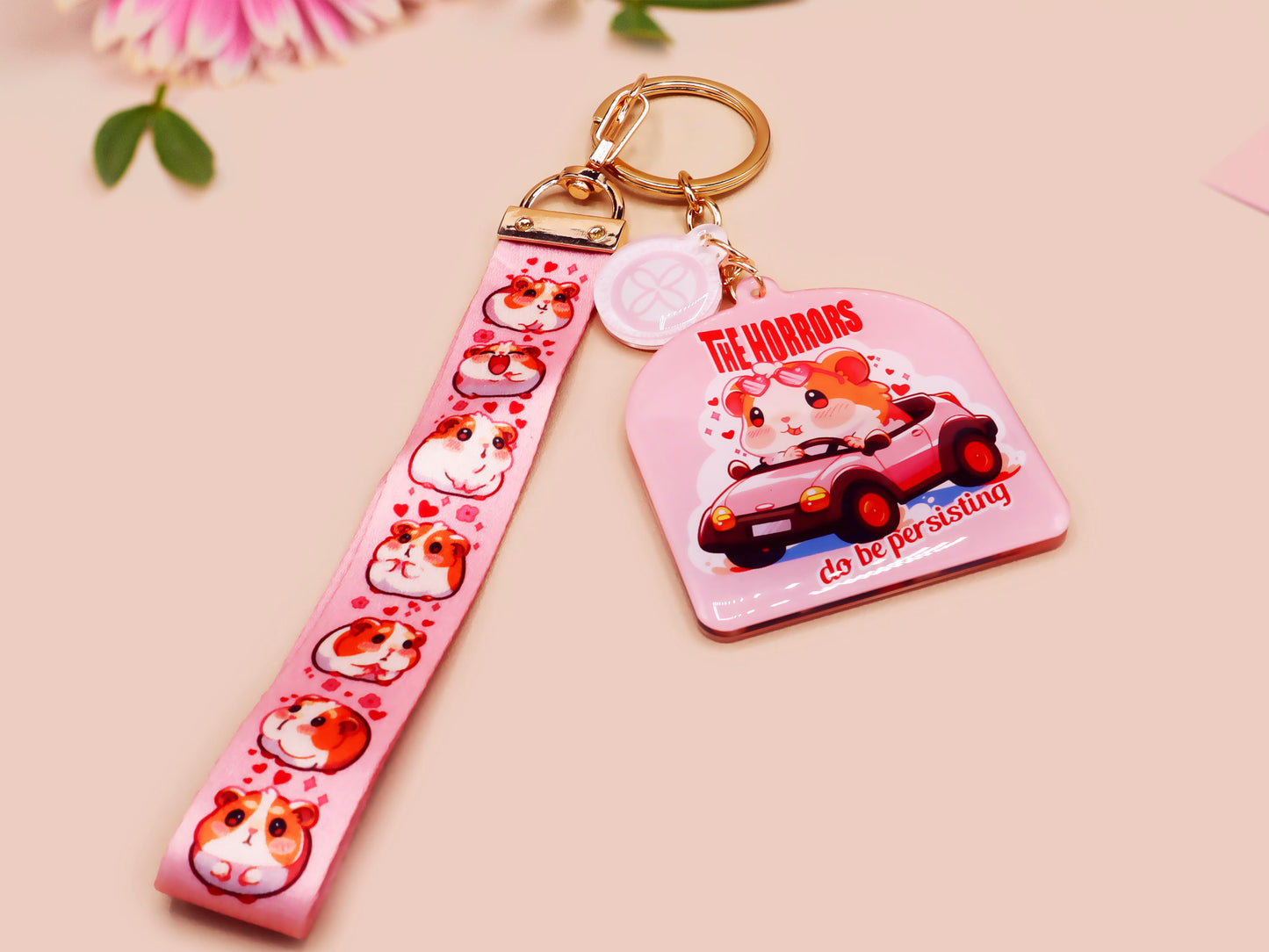 Cute pink keychain and lanyard of an adorable chibi hamster guinea pig in heart sunglasses driving a little pink car with the quote the Horrors do be persisting, with matching mini charm and lanyard of multiple cute fat guinea pig hamsters