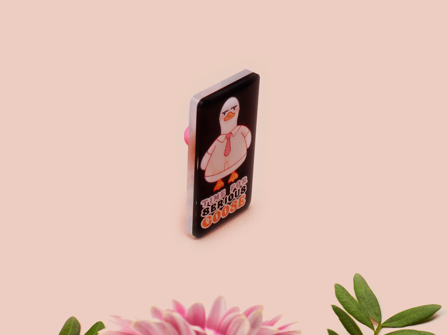 A black acrylic pin badge with a pink heart-shaped pin back clasp. The design of the pin badge is of a cute goose in a shirt and tie with the quote Time For Serious Goose