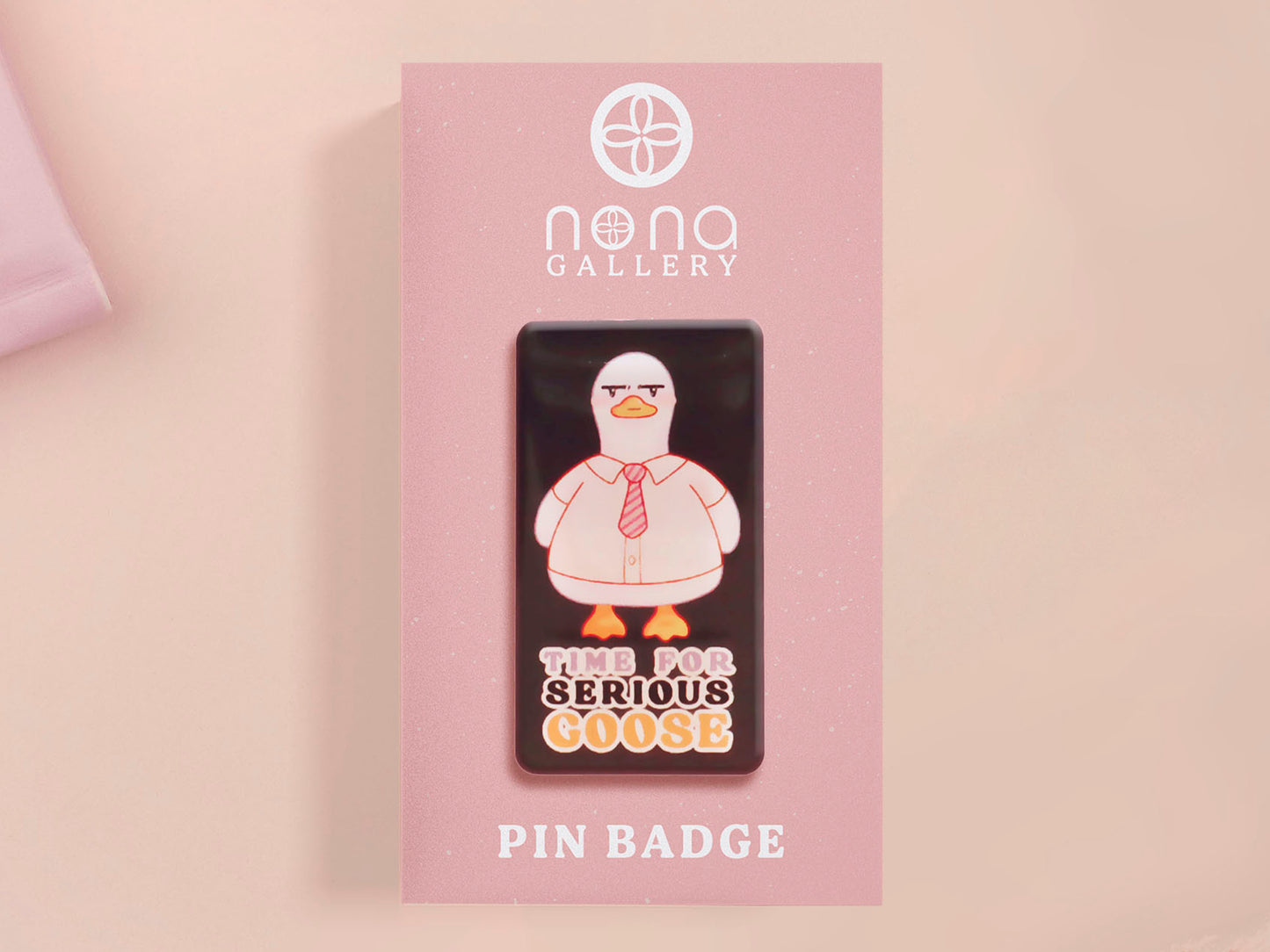 A black acrylic pin badge with a pink heart-shaped pin back clasp. The design of the pin badge is of a cute goose in a shirt and tie with the quote Time For Serious Goose
