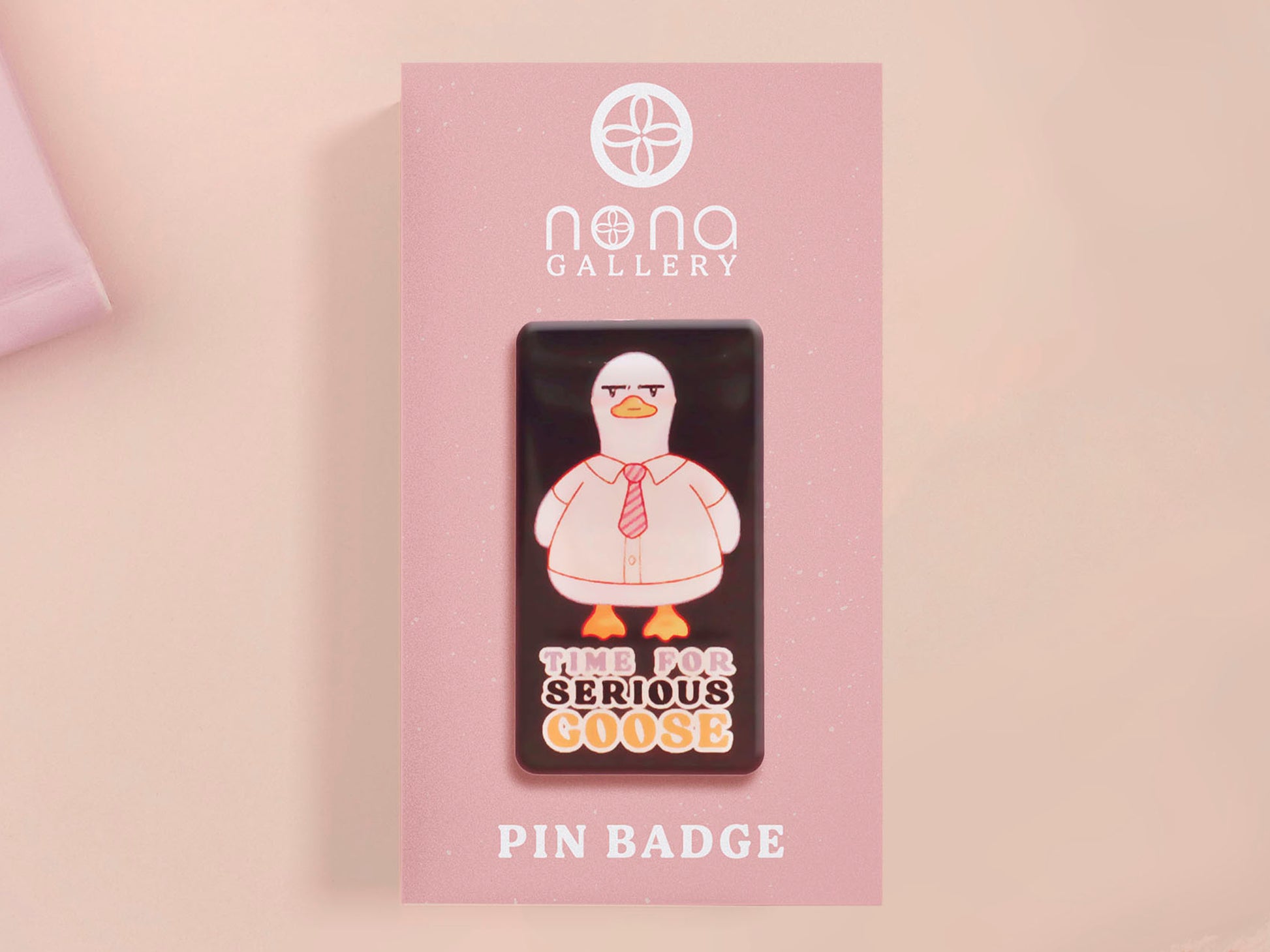 A black acrylic pin badge with a pink heart-shaped pin back clasp. The design of the pin badge is of a cute goose in a shirt and tie with the quote Time For Serious Goose