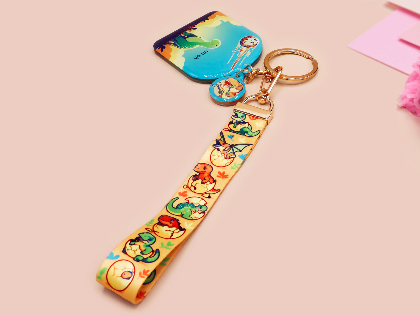 Acrylic epoxy dinosaur keychain with a large acrylic charm of a long necked dinosaur looking up at an incoming asteroid with the quote uh oh, a smaller charm of a cute trex with arm grabbers and a matching hatching baby dinosaur lanyard.
