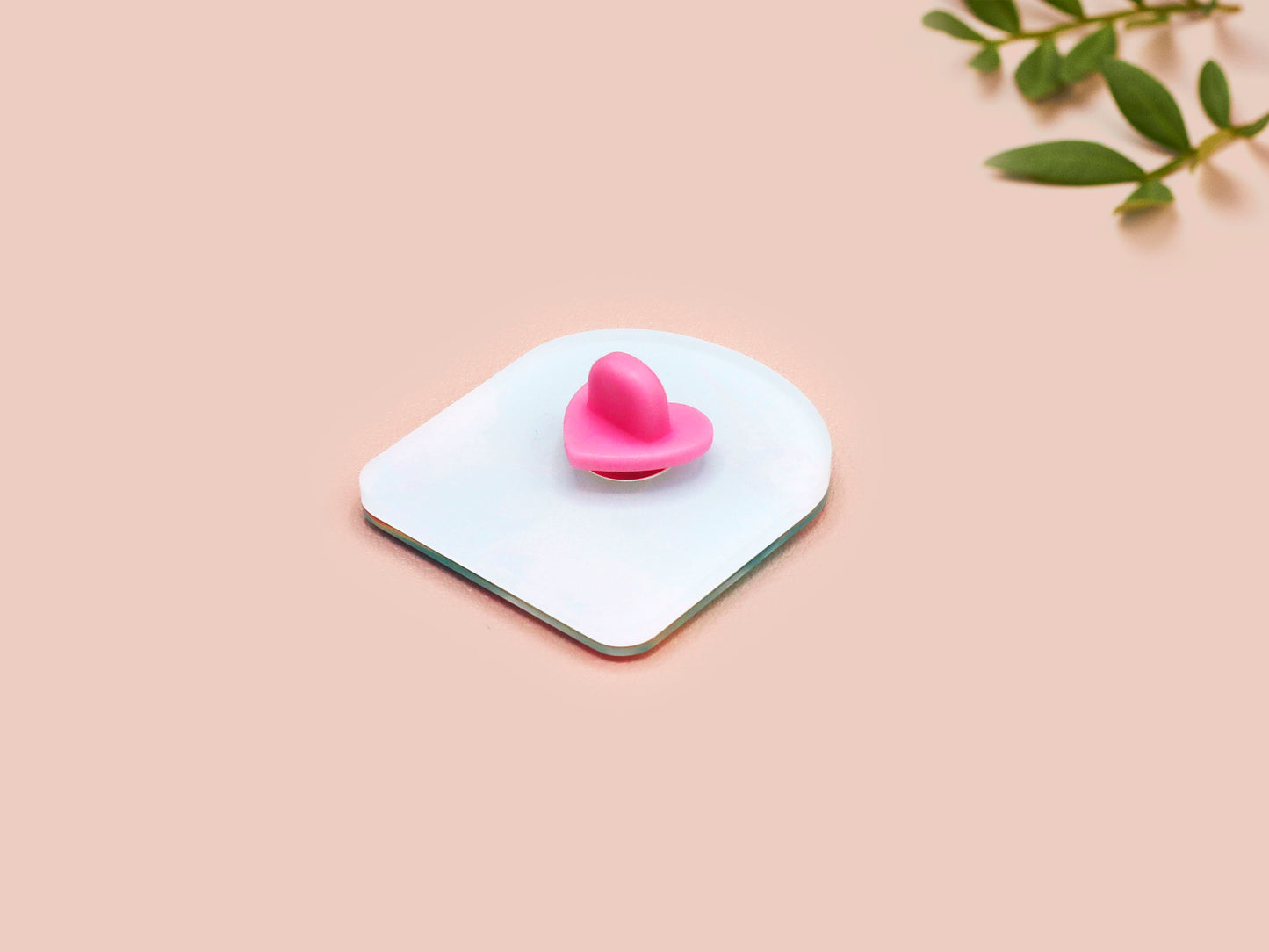 A clear acrylic pin badge with a pink heart-shaped pin back clasp. The design of the pin badge is of a cute long neck dinosur looking at an incoming asteroid with the quote uh oh.