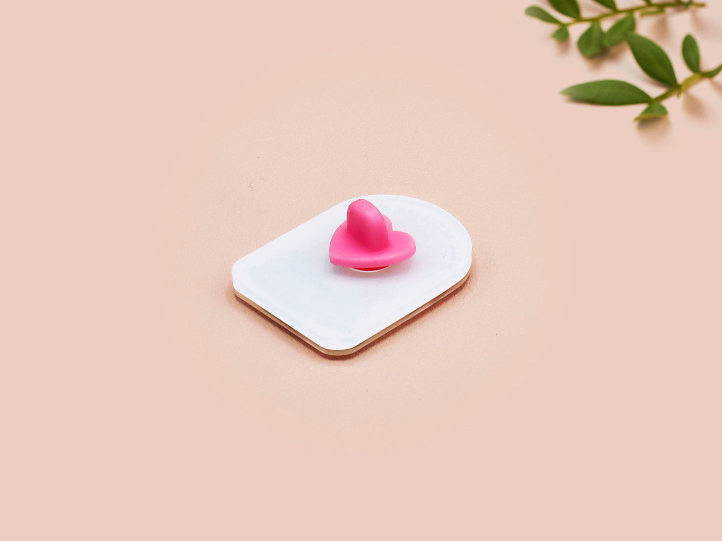 Clear acrylic pin badge with a pink heart-shaped rubber pin back clasp. The design of the pin badge is a cute chibi frog wearing a cowboy hat stetson and the quote well actually this is my first rodeo.