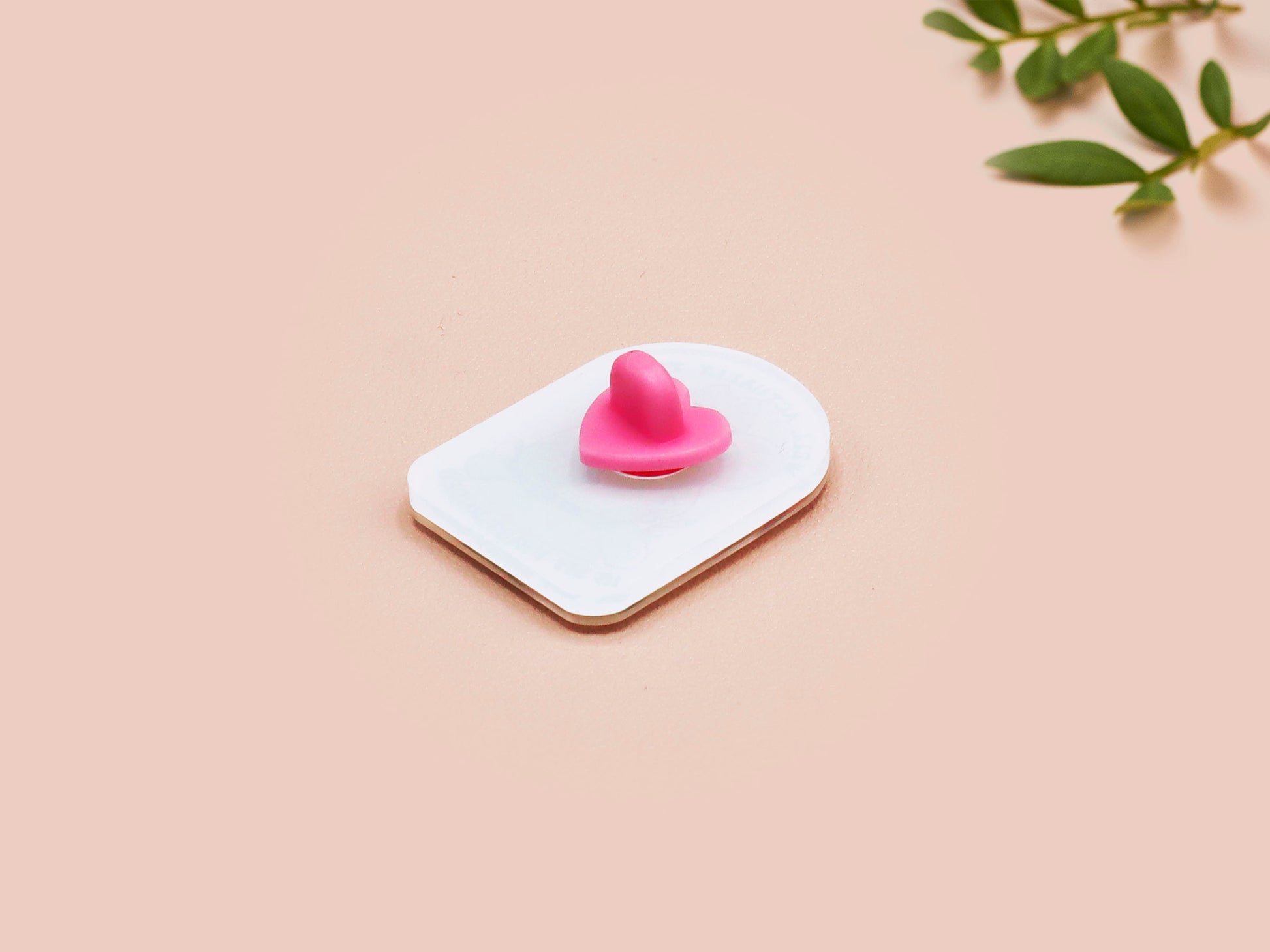 Clear acrylic pin badge with a pink heart-shaped rubber pin back clasp. The design of the pin badge is a cute chibi frog wearing a cowboy hat stetson and the quote well actually this is my first rodeo.
