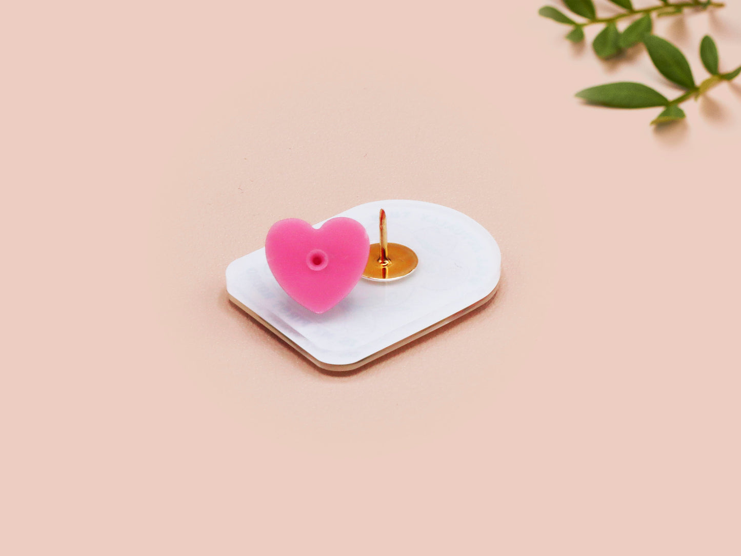 Clear acrylic pin badge with a pink heart-shaped rubber pin back clasp. The design of the pin badge is a cute chibi frog wearing a cowboy hat stetson and the quote well actually this is my first rodeo.