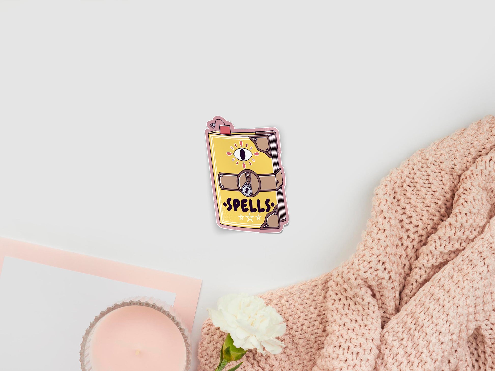 Large sticker of digital illustration cartoon yellow spell book with bookmark and eye, and the word spells written on the front cover, closed with a padlock