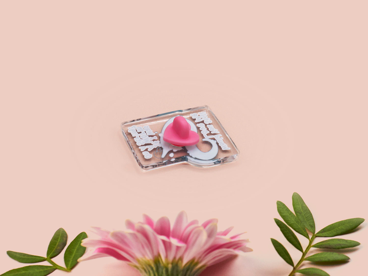 A clear acrylic pin badge with a pink heart-shaped rubber pin back clasp. The pin badge has a design of a cute blue crying worm on a string with the quote would you still love me if I was a worm on a string?