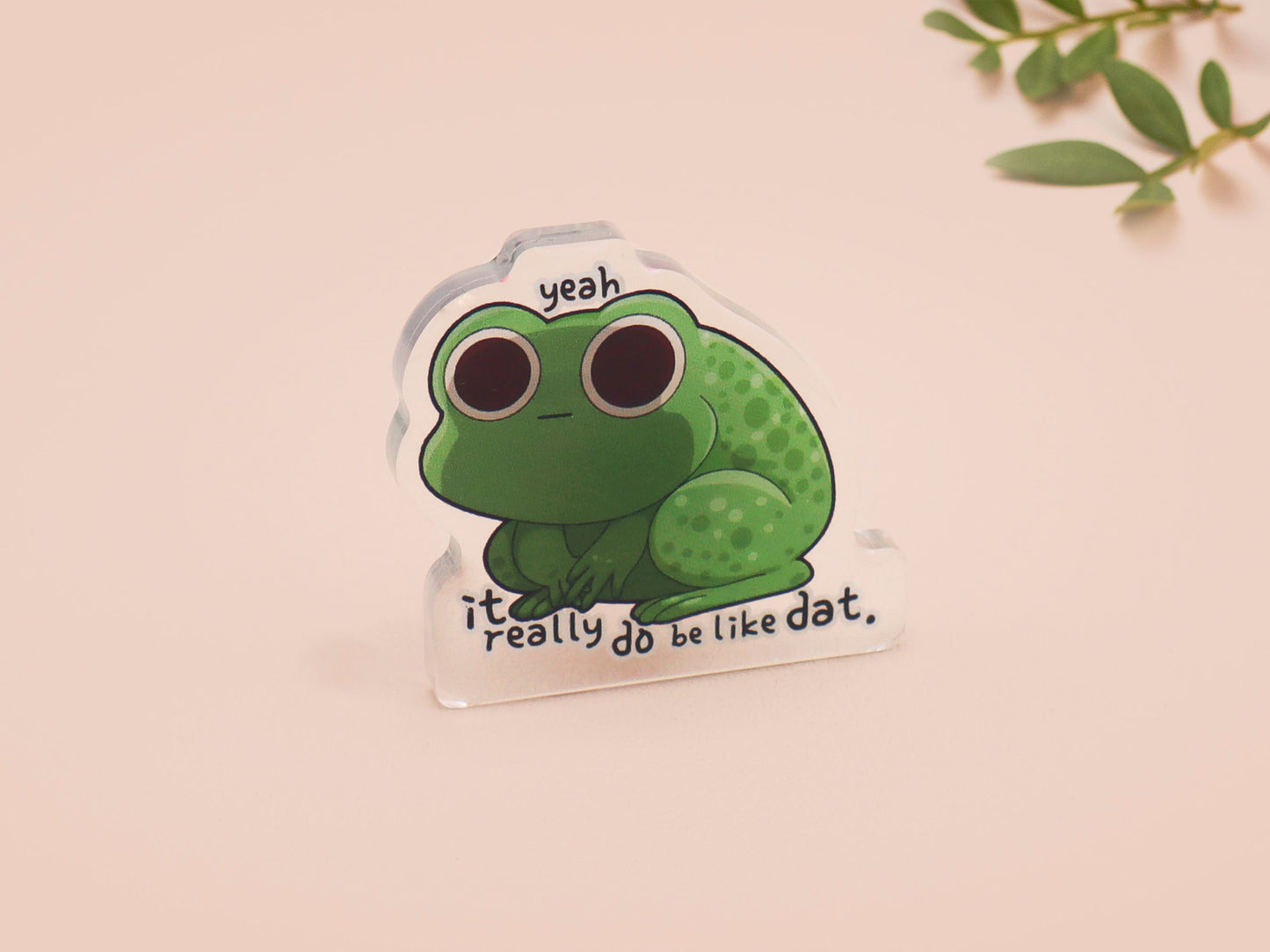 Clear acrylic pin badge with a pink heart-shaped rubber pin back clasp. The design of the pin badge is a cute cartoon stressed frog with the quote yeah it really do be like dat.