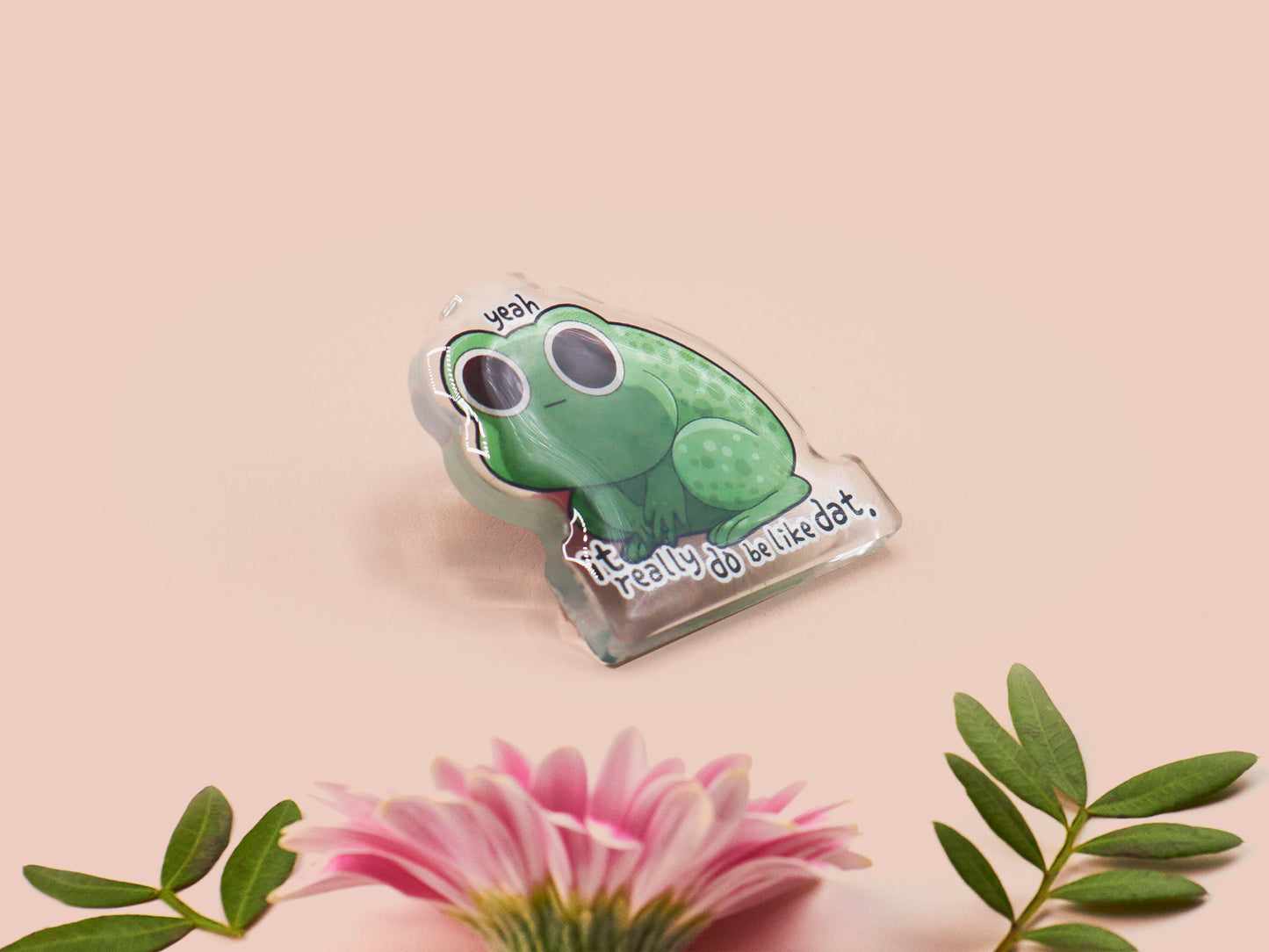Clear acrylic pin badge with a pink heart-shaped rubber pin back clasp. The design of the pin badge is a cute cartoon stressed frog with the quote yeah it really do be like dat.