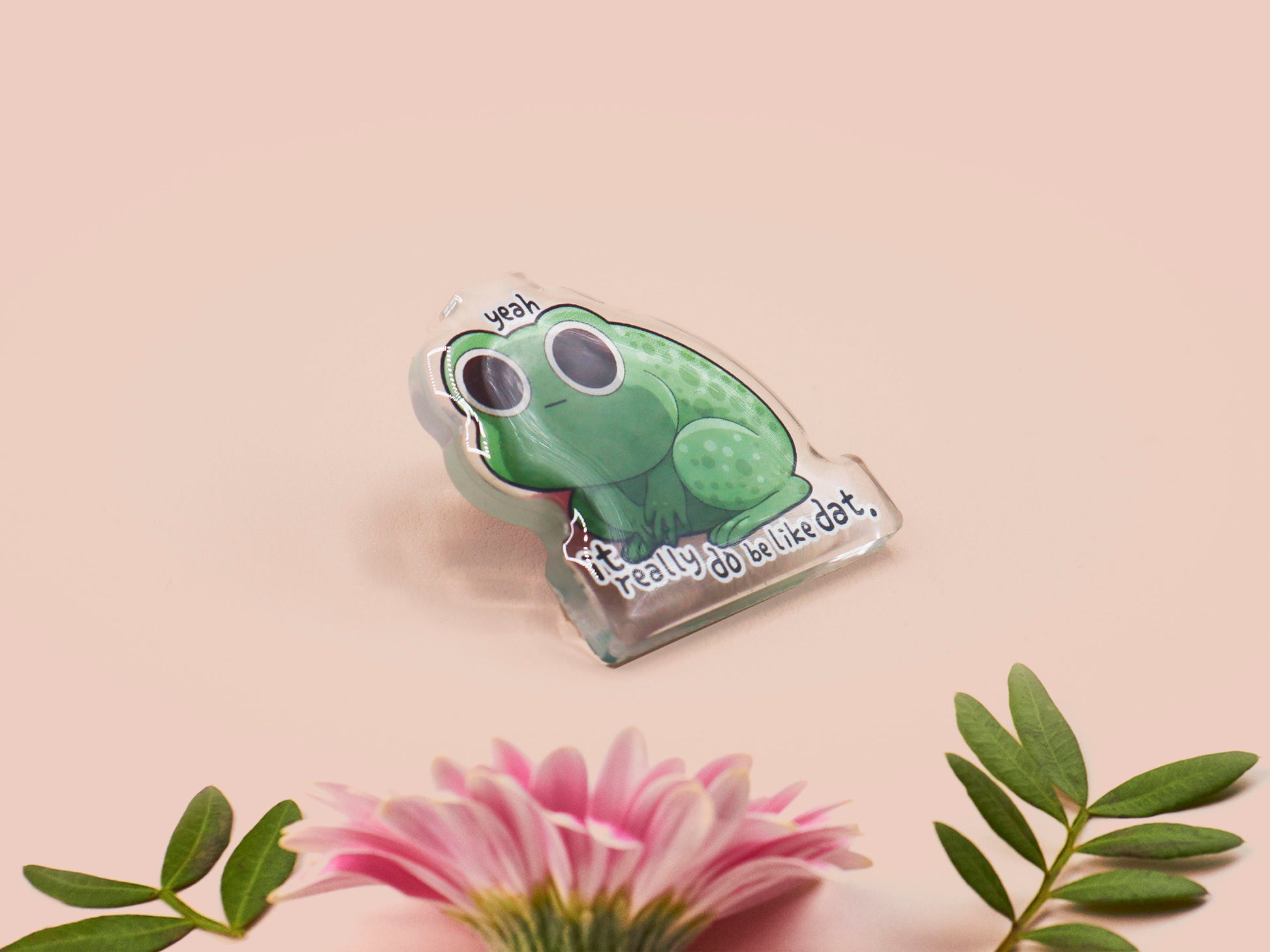 Clear acrylic pin badge with a pink heart-shaped rubber pin back clasp. The design of the pin badge is a cute cartoon stressed frog with the quote yeah it really do be like dat.