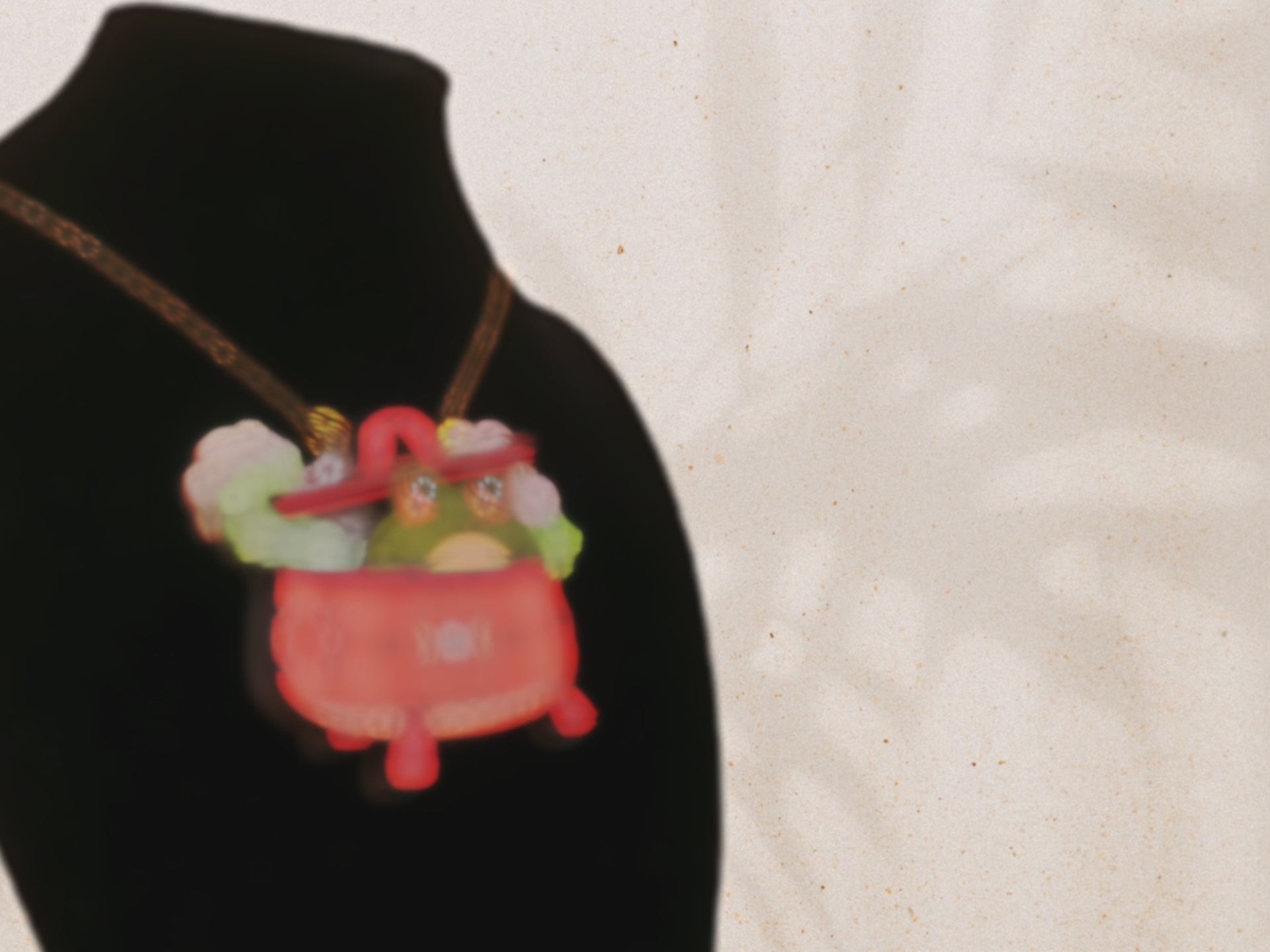 Video of front and back of mixed material handmade necklace of chibi cartoon frog sat inside a bubbling pearlescent witch's cauldron, with a gold chain and black gift box with a green familiars collection gift sleeve.