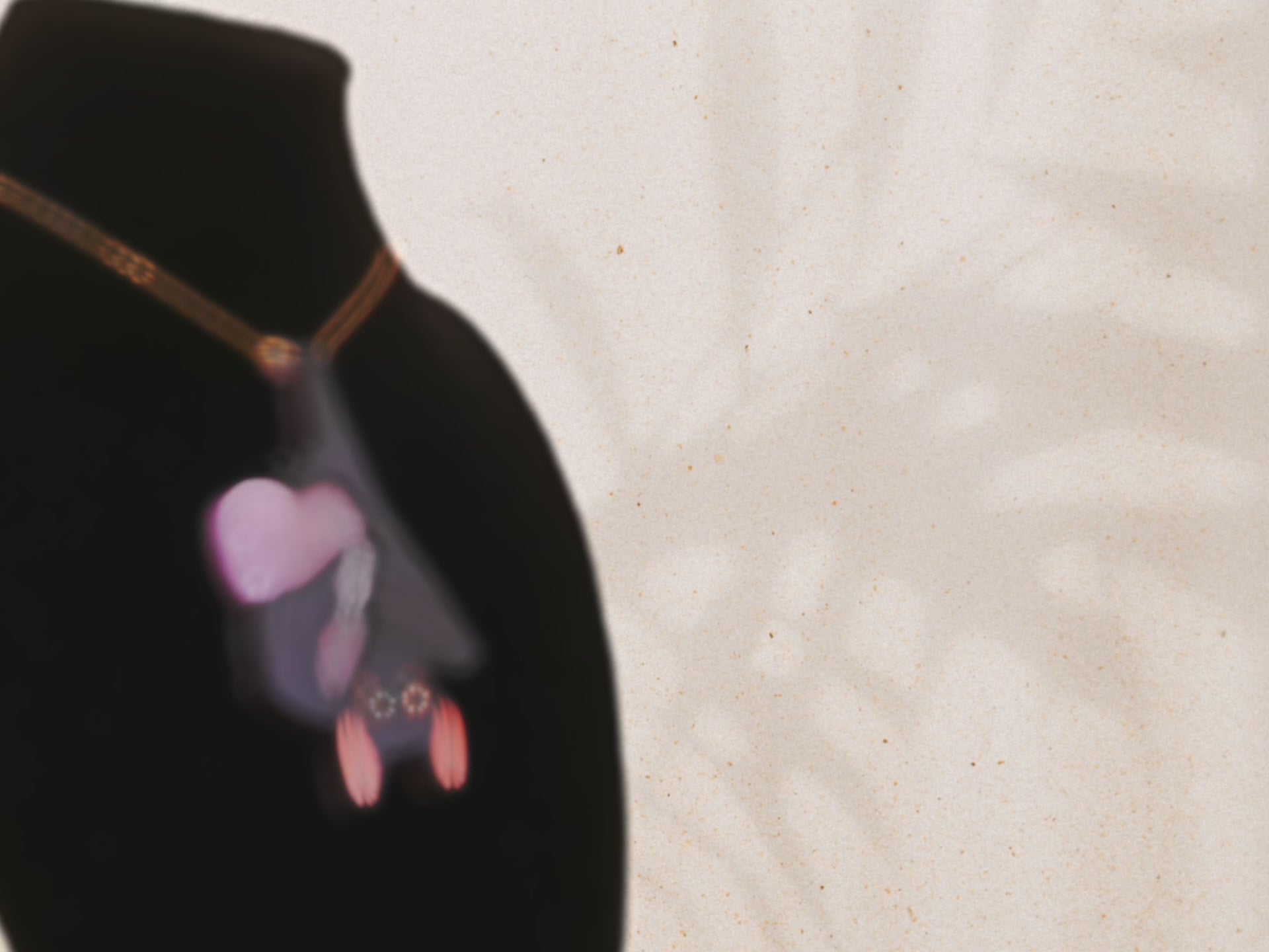 Video of mixed material handmade necklace of chibi cartoon bat hanging upside down holding a pearlescent Ouija planchette with a gold chain and necklace extender on black jewellery bust.
