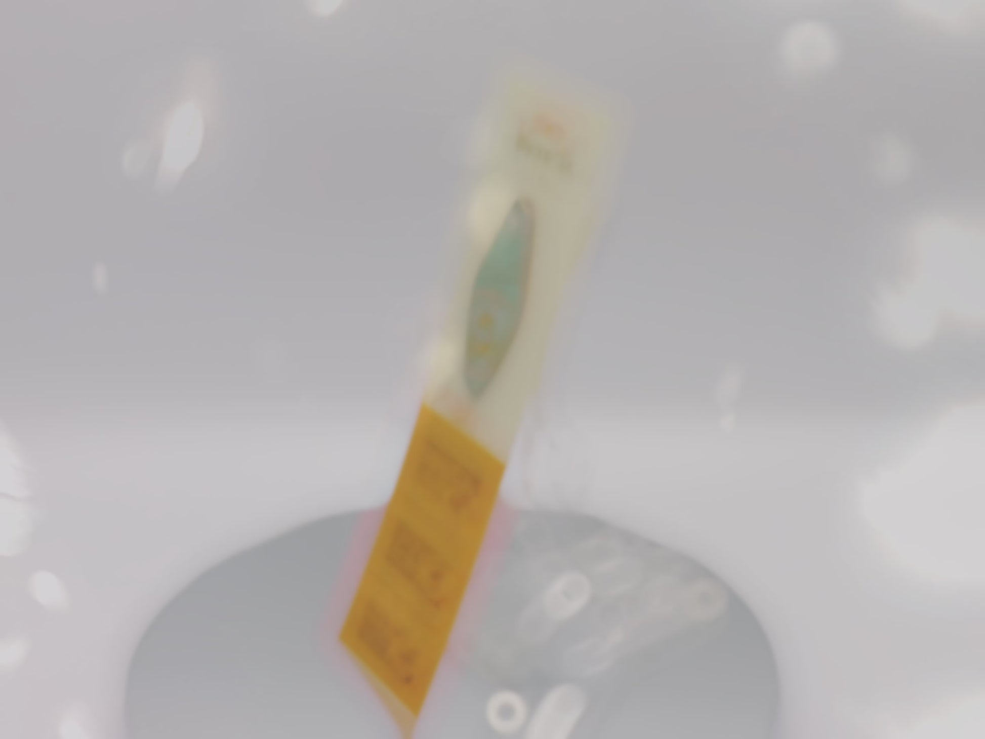 Video of front and back of gold Enamel Talisman Pin with blue design and the words Writer's Talisman sits on a long white and yellow backing card with gold accents. The backing card has details the symbolism of the different design elements of the Talisman pin.