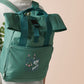 Green roll top twin handle backpack with an embroided design of cute gelatinous cube DND monster and the quote Bag of Holding