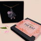 Mixed material handmade necklace of chibi cartoon bat hanging upside down holding a pearlescent Ouija planchette, with a gold chain and black gift box with a pink familiars collection gift sleeve.