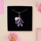 Mixed material handmade necklace of chibi cartoon bat hanging upside down holding a pearlescent Ouija planchette, with a gold chain and black gift box.