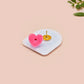 Clear acrylic pin badge with pink heart-shaped rubber pin back clasp. The design of the pin badge is a cute cartoon chibi fresno nightcrawlers, yeti bigfoot and alien UFO in a forest with the quote Be The Cryptid You Want To See In The Woods.