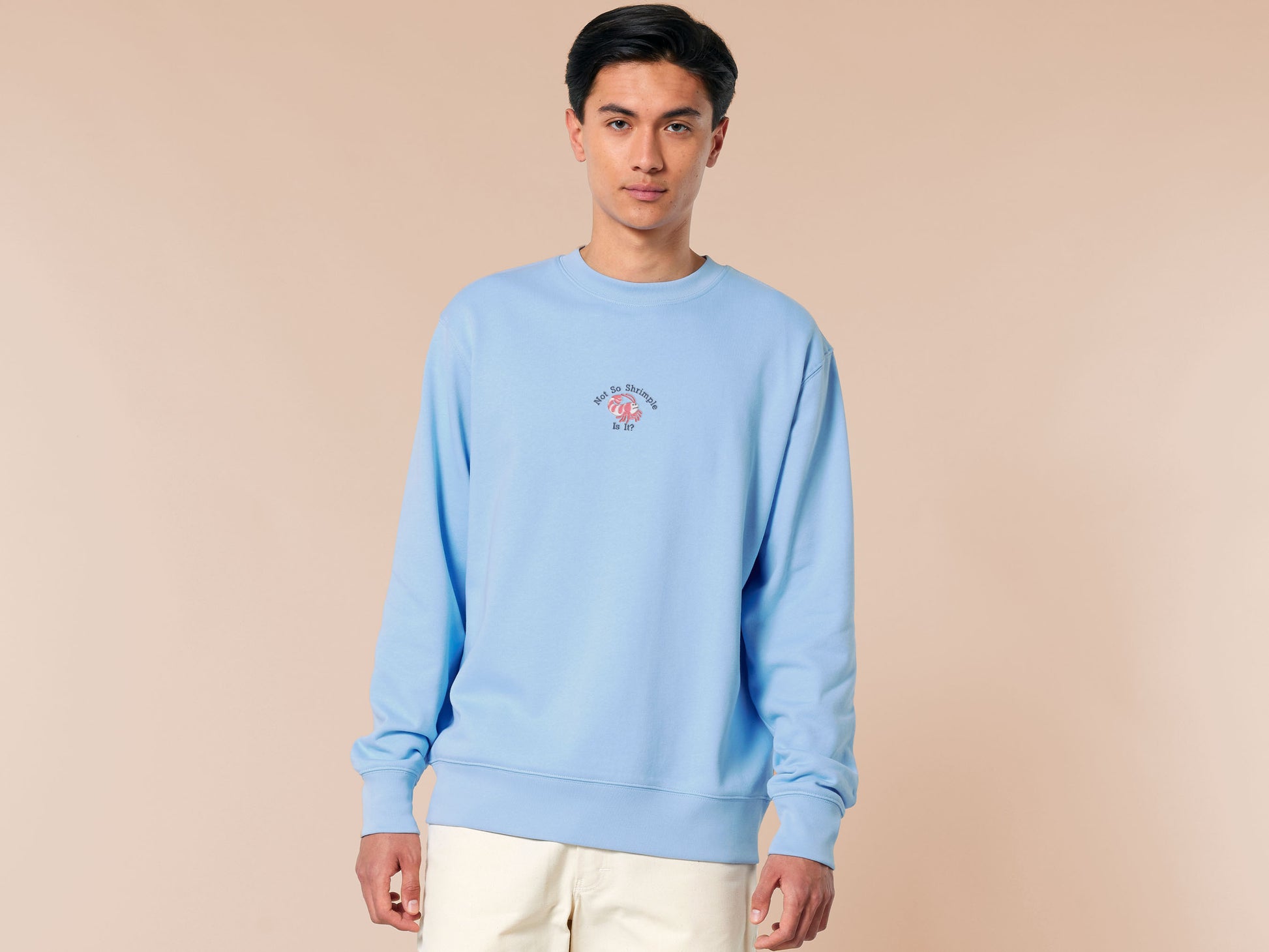 A blue long sleeve sweater, with an embroidered chibi shrimp looking concerned and the quote Not so shrimple is it?