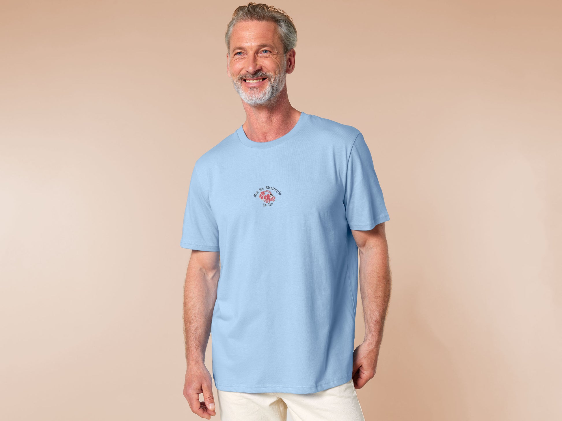 A blue short sleeve tshirt, with an embroidered chibi shrimp looking concerned and the quote Not so shrimple is it?