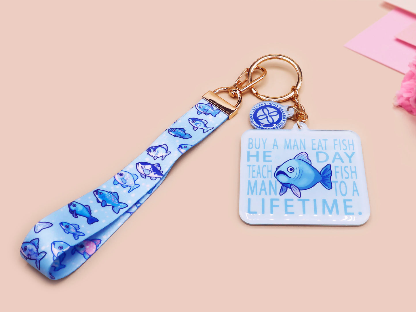Acrylic epoxy underwater fish keychain with a large acrylic charm of a blue fish with the quote buy a man eat fish he day teach fish man to a lifetime, a smaller charm of a cute fish and a matching underwater lanyard.