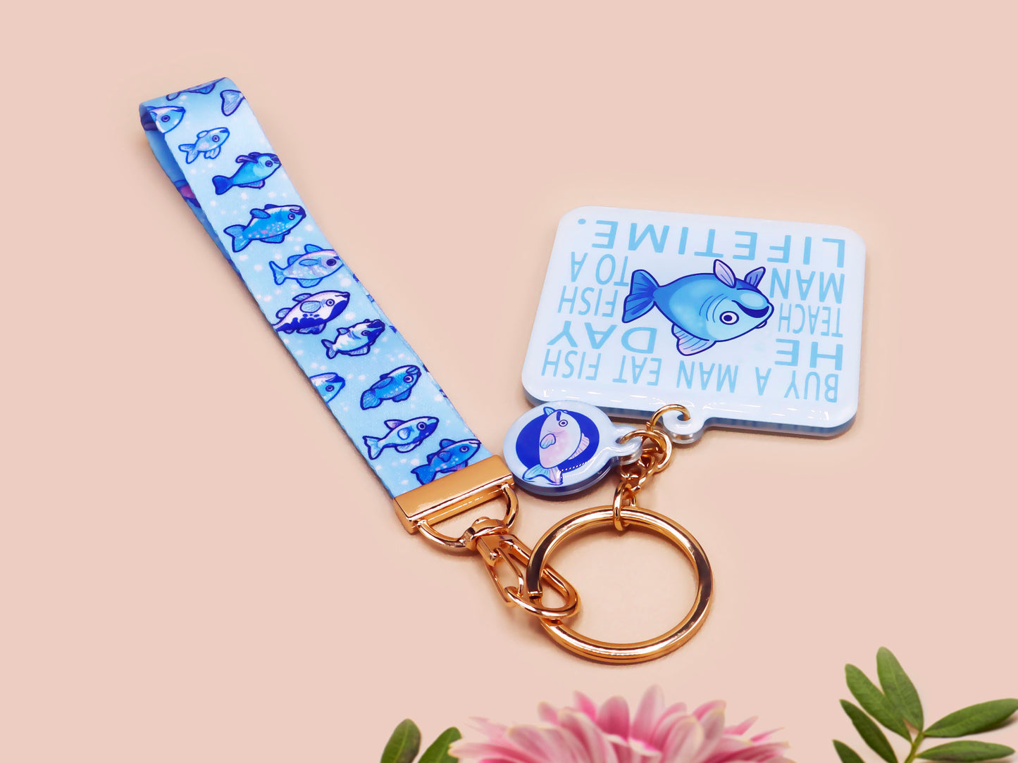 Acrylic epoxy underwater fish keychain with a large acrylic charm of a blue fish with the quote buy a man eat fish he day teach fish man to a lifetime, a smaller charm of a cute fish and a matching underwater lanyard.