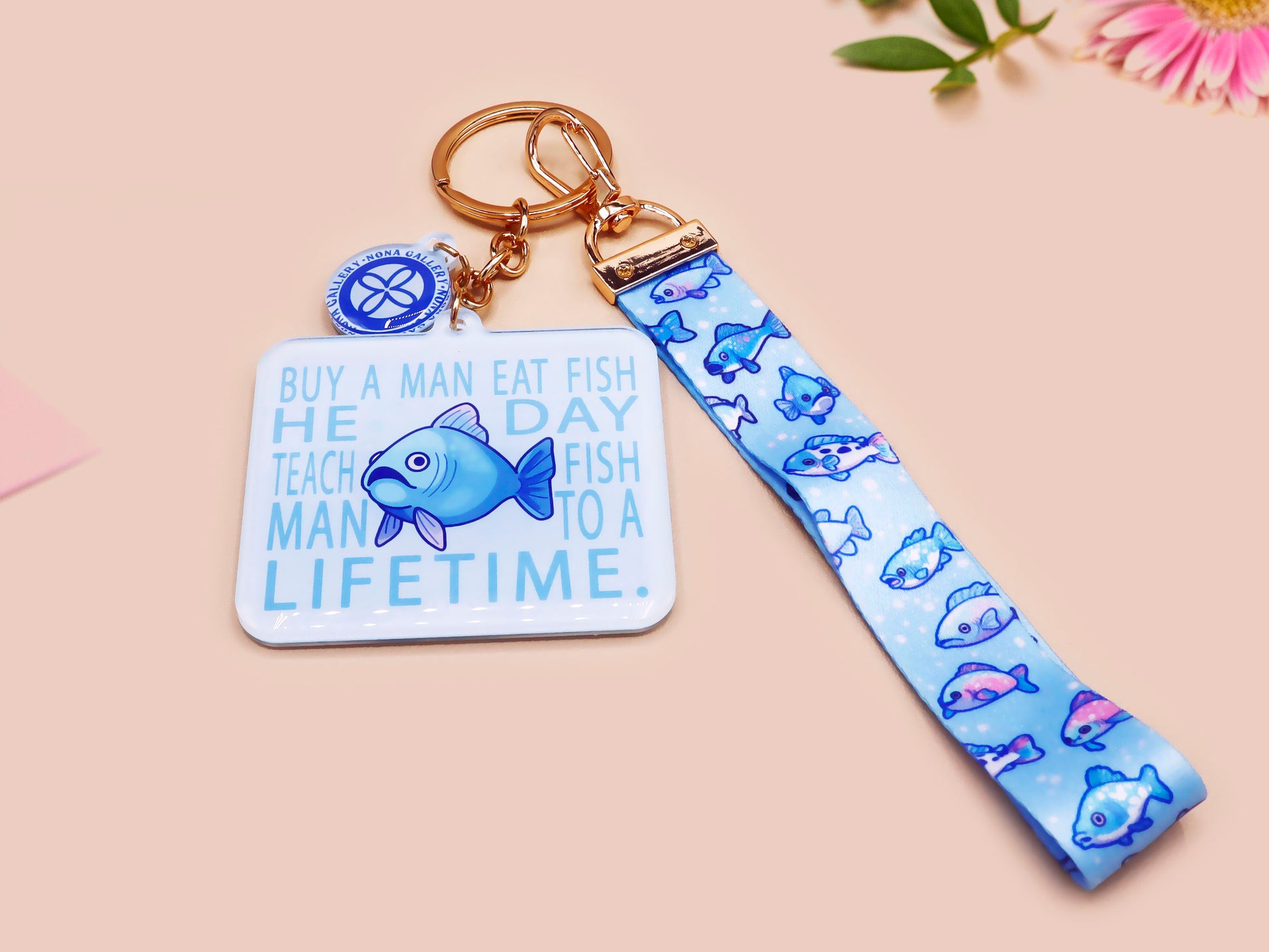 Acrylic epoxy underwater fish keychain with a large acrylic charm of a blue fish with the quote buy a man eat fish he day teach fish man to a lifetime, a smaller charm of a cute fish and a matching underwater lanyard.
