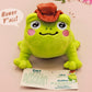 An adorable green frog plushie toy with cute embroidered eyes and facial expression, wearing a cowboy hat with a brown ribbon, and a hang tag describing the frog as Carl.