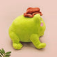 An adorable green frog plushie toy with cute embroidered eyes and facial expression, wearing a cowboy hat with a brown ribbon, and a hang tag describing the frog as Carl.