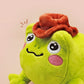 An adorable green frog plushie toy with cute embroidered eyes and facial expression, wearing a cowboy hat with a brown ribbon, and a hang tag describing the frog as Carl.