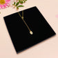 A wooden and glitter acrylic necklace with gold chain in a black box of two cute frogs sat on a log smiling surrounded by flowers, plants and mushrooms