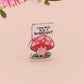 This cute transparent acrylic pin badge has a pink rubber heart shrimp pin-back clasp. The design is of a chibi cartoon mushroom with the text "Come back with a warrant."