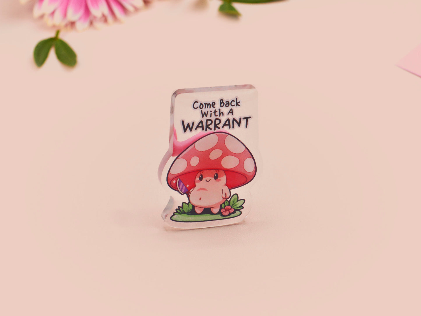 This cute transparent acrylic pin badge has a pink rubber heart shrimp pin-back clasp. The design is of a chibi cartoon mushroom with the text "Come back with a warrant."