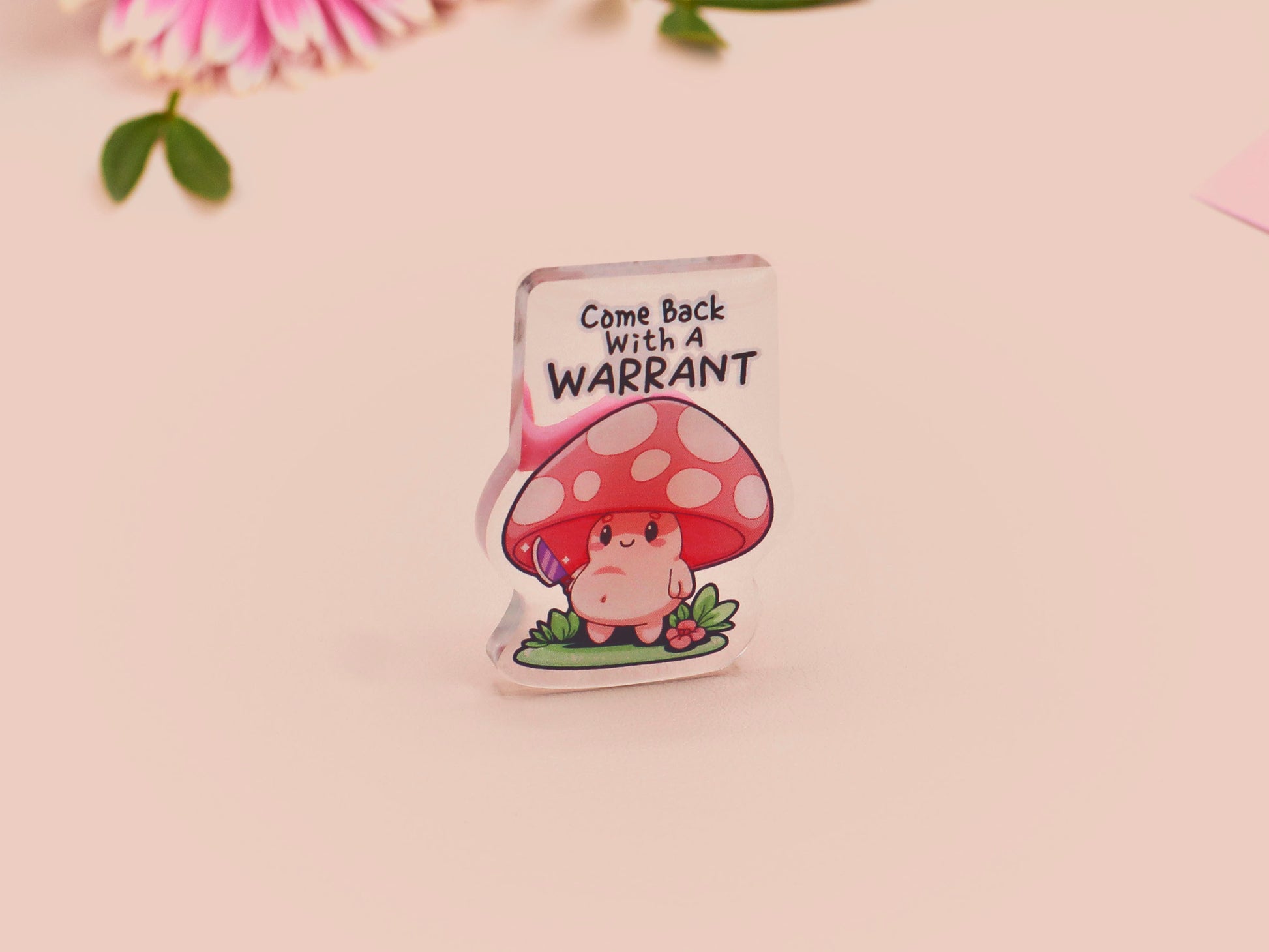 This cute transparent acrylic pin badge has a pink rubber heart shrimp pin-back clasp. The design is of a chibi cartoon mushroom with the text "Come back with a warrant."