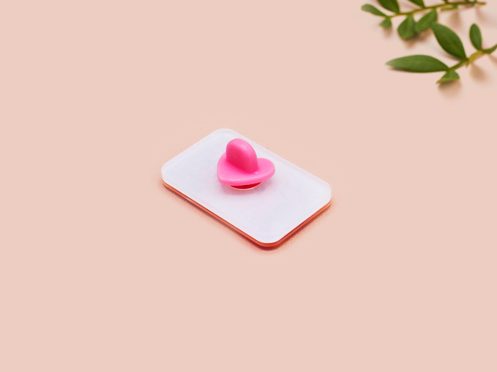 A clear acrylic pin badge with a pink heart-shaped pin back clasp. The design of the pin badge is of a cute singing cowboy cat from the viral internet meme with the song quote Country roads take me home to the place I belong