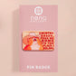 A clear acrylic pin badge with a pink heart-shaped pin back clasp. The design of the pin badge is of a cute singing cowboy cat from the viral internet meme with the song quote Country roads take me home to the place I belong