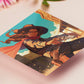 A square art print depicting a cowgirl gunslinger in a dramatic pose in the wild west outside a saloon.