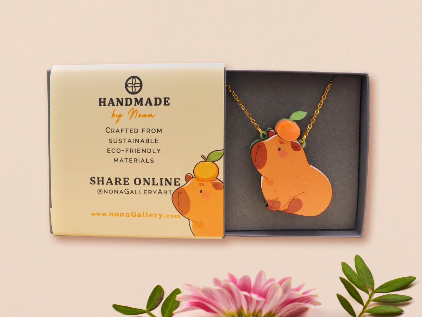 Adorable cute capybara with an orange on its head necklace made of wood and glitter pearlescent acrylic with a gold chain, displayed in a velvet gift box with a unique cute capybara sleeve design.