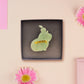 Adorable cute capybara with an orange on its head brooch pin badge made of wood and glitter pearlescent acrylic with a gold fastener, displayed in a velvet gift box with a unique cute capybara sleeve design.