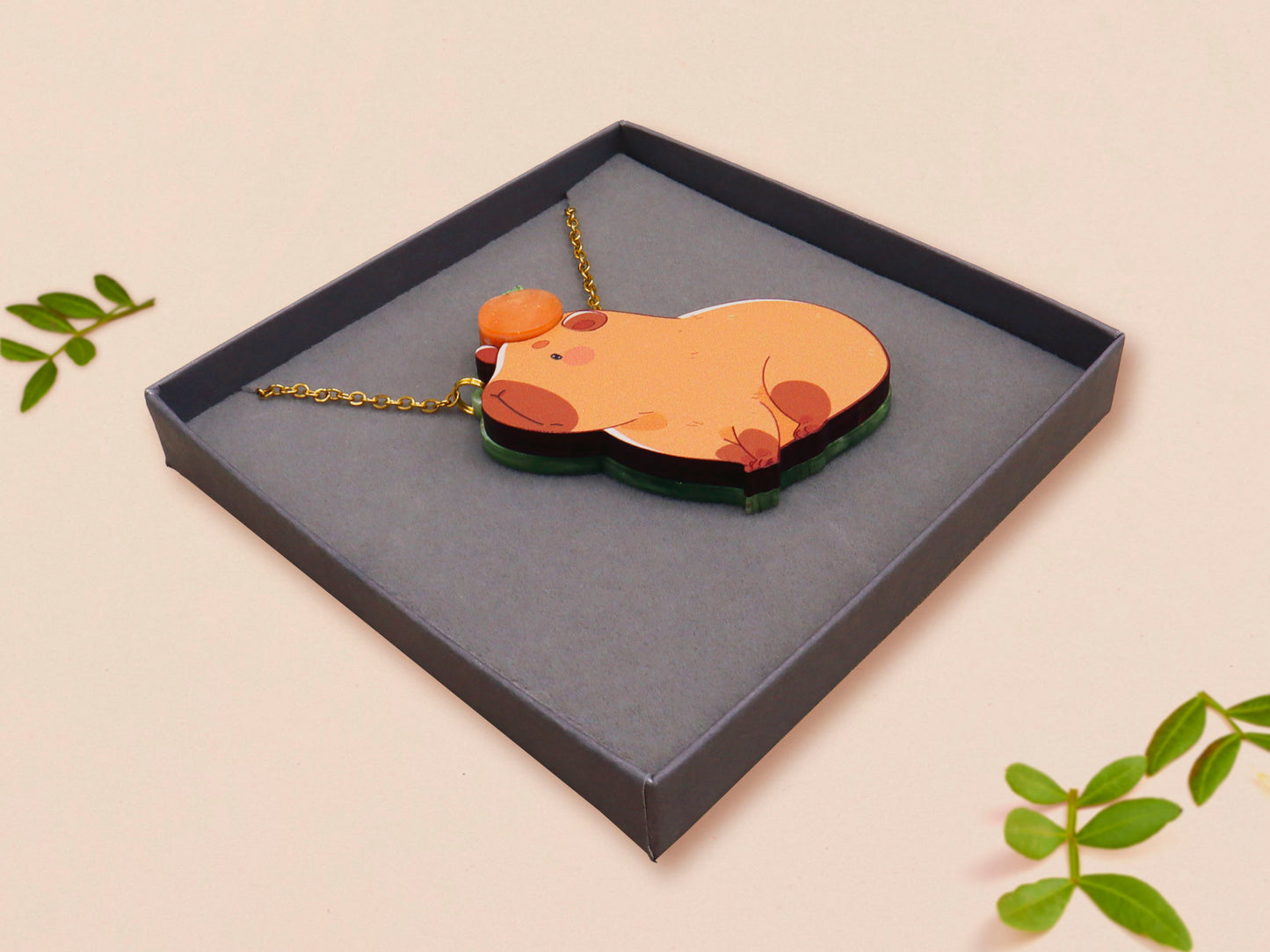 Adorable cute capybara with an orange on its head necklace made of wood and glitter pearlescent acrylic with a gold chain, displayed in a velvet gift box with a unique cute capybara sleeve design.