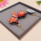 An adorable cute dachshund sausage dog necklace in a french outfit, a beret and striped top, connected to a speech bubble that is engraved with the words oui oui! displayed in a velvet gift box with a unique cute dachshund sleeve design.